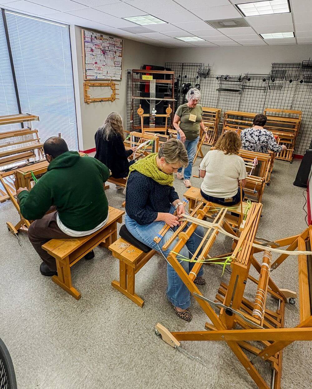 a classroom of people weave on floor looms
