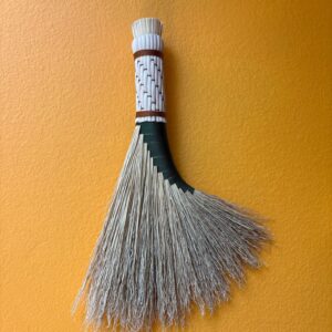 a beautiful broom hangs on a yellow wall